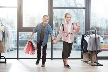 happy children with shopping bags making selfie at shop