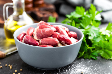 Fresh raw chicken hearts on dark background