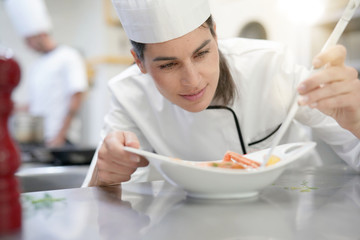 Professional cook garnishing plate in restaurant kitchen
