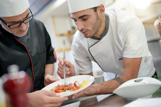 Professional cook chefs in kitchen improving dish composition