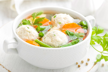 Fresh chicken soup with vegetables and meatballs in a bowl on white background. Top view