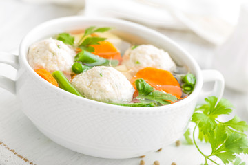 Fresh chicken soup with vegetables and meatballs in a bowl on white background. Top view