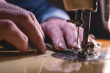 Sewing process of the leather belt. old Man's hands behind sewing. Leather workshop. textile vintage sewing industrial