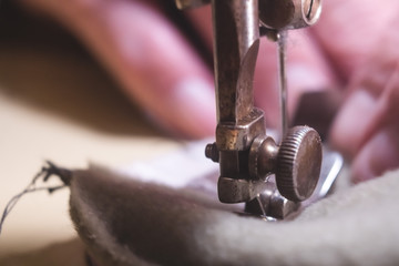 Sewing process of the leather belt. old Man's hands behind sewing. Leather workshop. textile vintage sewing industrial