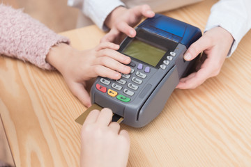 cropped view of kid paying with credit card in payment terminal