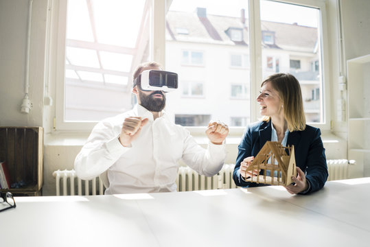 Woman and man with house model and VR glasses in office