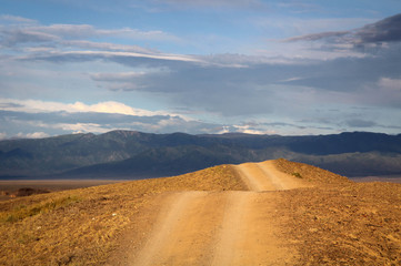 The road stretches into the distance mountains in the background.  Kazakhstan. Charyn canyon.