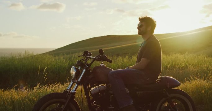 Man on vintage motorcycle watching the sunset