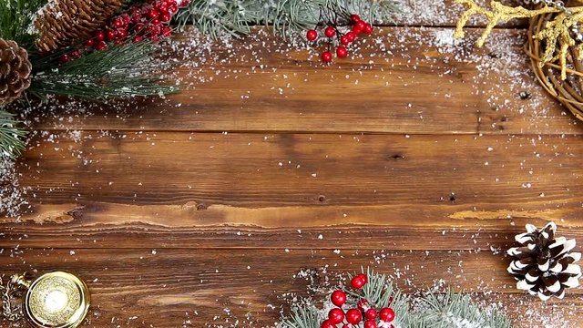 Christmas wooden background with snowy branch Top view. The hands of a young girl put a gift with a red bow on the table