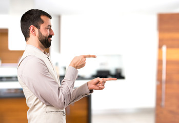 Handsome man with vest pointing to the lateral inside house