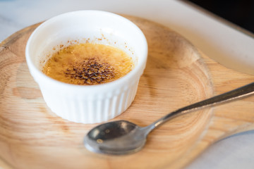Creme Brulee, also known as burnt cream, a dessert with rich custard base and topped by caramel, on wooden plate