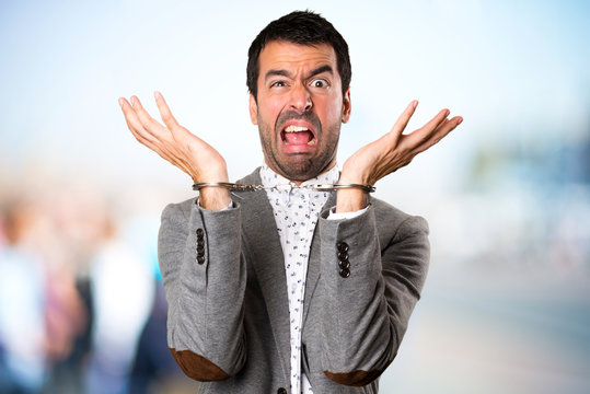 Frustrated Handsome man with handcuffs on unfocused background