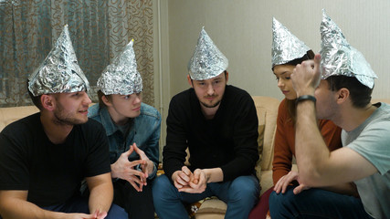 Friends in foil on the head of the house. Gathering of friends about listening to their ideas of extraterrestrial civilizations © Media Whale Stock