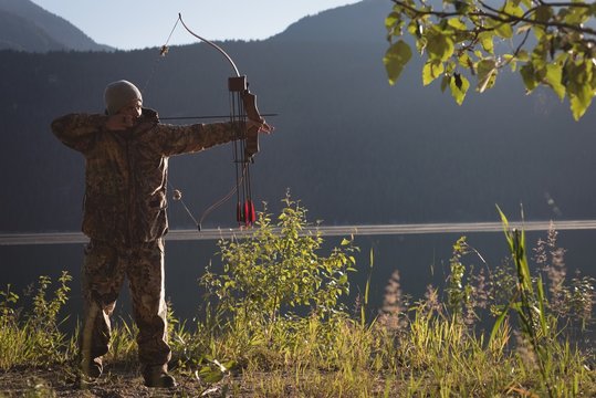 Archer aiming with bow and arrow in the forest