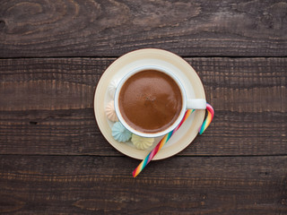 Cocoa with foam, sweet candy and colored bisse on a wooden table