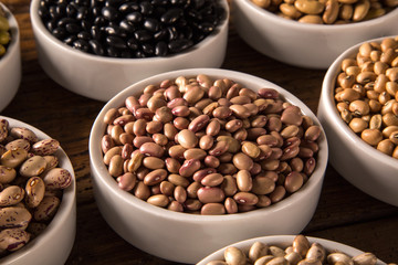 Assorted beans in bowls on wood background
