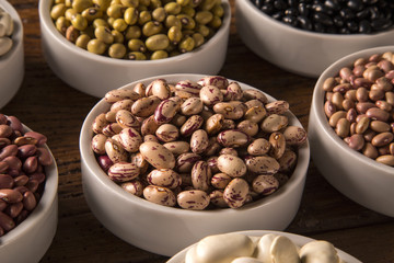 Assorted beans in bowls on wood background
