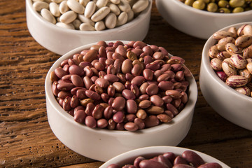 Assorted beans in bowls on wood background