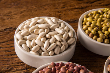 Assorted beans in bowls on wood background
