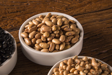 Assorted beans in bowls on wood background