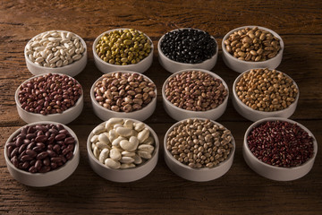 Assorted beans in bowls on wood background