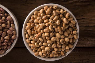Assorted beans in bowls on wood background