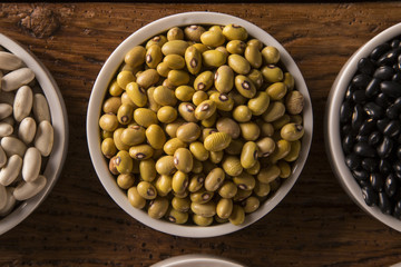 Assorted beans in bowls on wood background