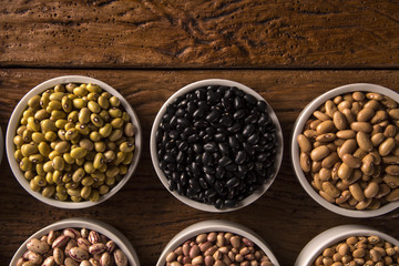 Assorted beans in bowls on wood background