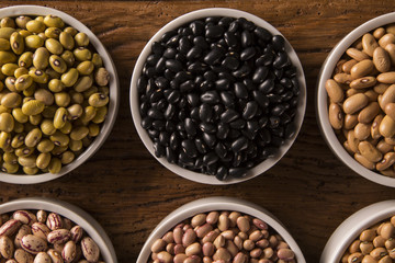 Assorted beans in bowls on wood background