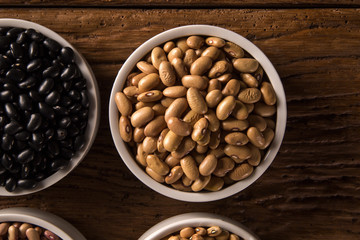 Assorted beans in bowls on wood background
