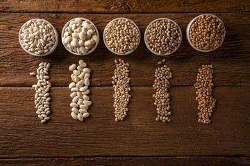Assorted beans in bowls on wood background