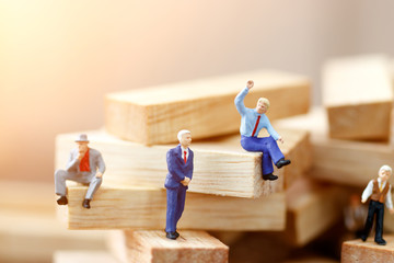 Miniature business people sitting on wood block, recruitment and business concept.