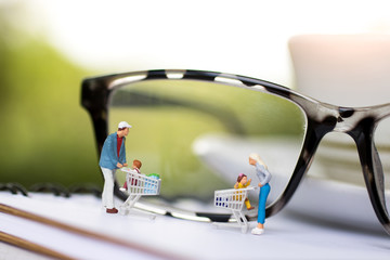 Concept of tourism, shopping or business. Miniature people family with shopping cart on book..