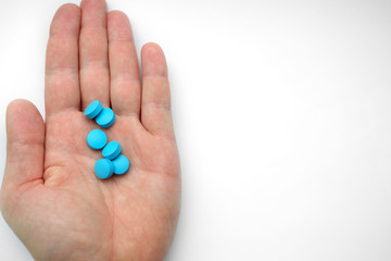 hand of man holding blue pills