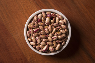 beans into a bowl on wooden background