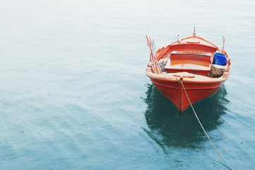 Obraz premium Red Mediterranean fishing boat in the sea in summer cloudy day. Lonely red boat