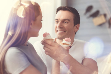 Take a bite. Two young energetic joyful people having fun feeding each others muffins while enjoying the morning together