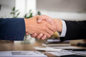 Two smiling businessman shaking hands together after good deal connection to join investment business