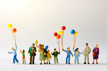 Miniature people with family holding balloon  on the map with sunlight, happy family day concept.