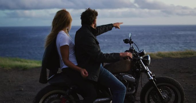 Couple on vintage motorcycle watching the sunset