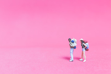 Miniature people : Couple of travellers on pink background , Valentine's day concept