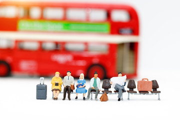 Miniature people with baggage waiting for bus. Transportation, traveling or business trip concepts.