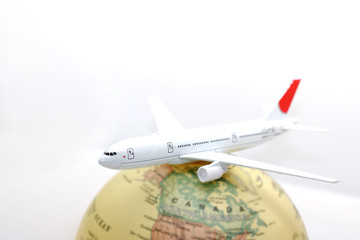 Miniature white airplane on globe, travel concept.
