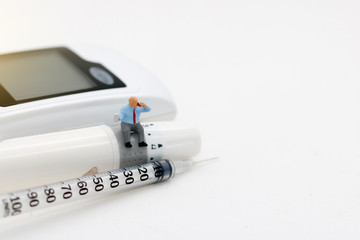 Miniature people sitting on  glucose meter of diabetes and syringe. Healthcare, Medical  and business concept.