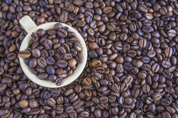 Fototapeta premium cup with coffee beans on coffee beans background top view