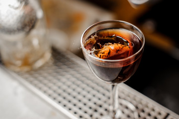 Glass filled with alcoholic drink with a slice of fresh orange