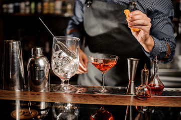 Barman making a fresh alcoholic cocktail with a fresh orange juice