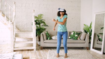 Happy smiling young mixed race girl getting experience using VR headset glasses of virtual reality...