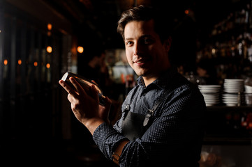 Handsome bartender holding a shaker in hand