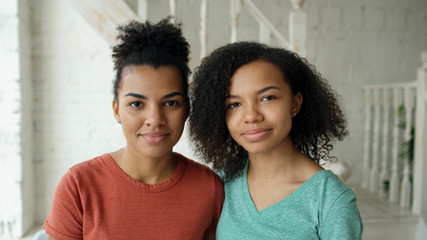 Portrait of two beautiful african american girls smiling and looking into camera at home